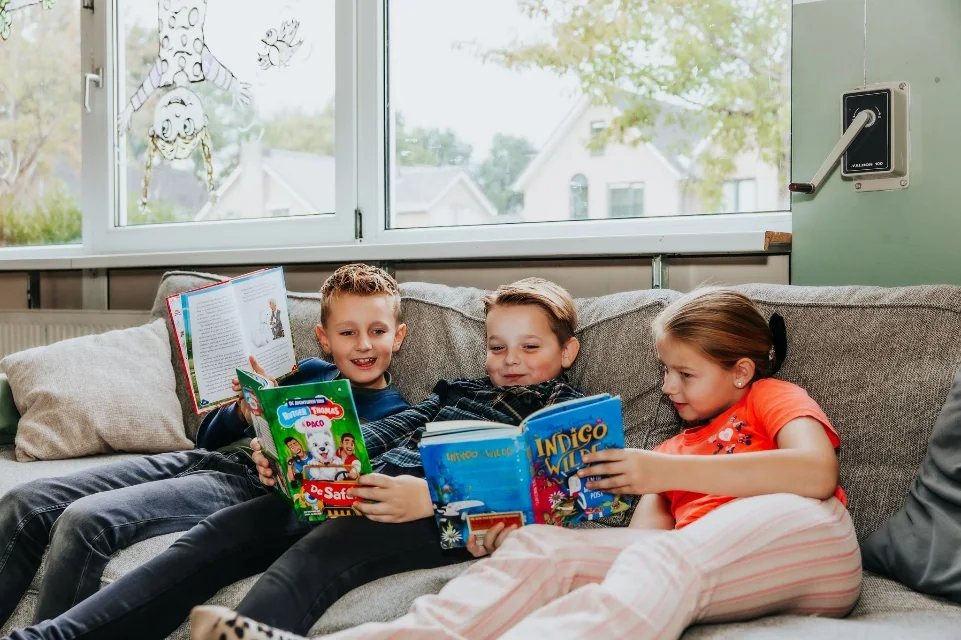 Oudere kinderen lezen op de bank